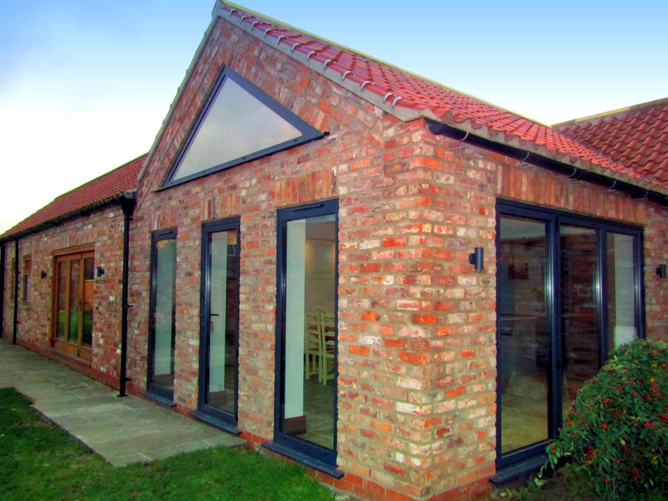 Converted barn with glass doors and full length windows
